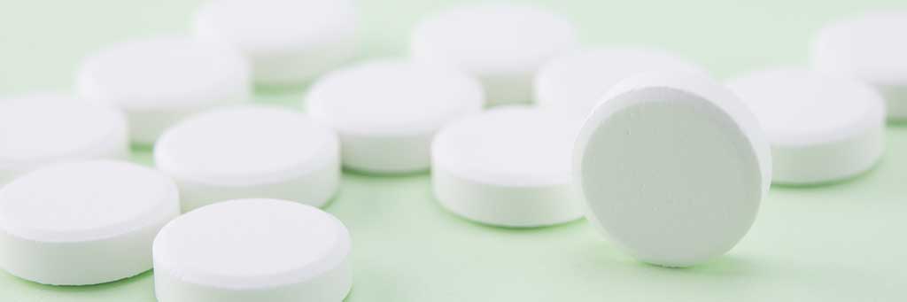 white pills on green background, selective focus
